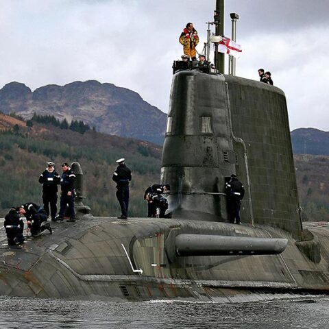 Royal Navy submariners stand on top of their submarine